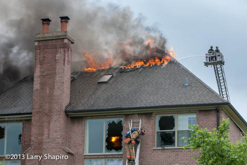 fire burns through the roof of a house