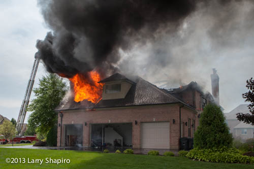 fire blows out the roof of a house