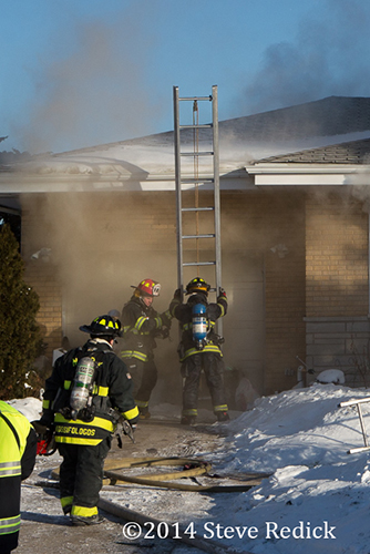 firemen place ladder at house fire