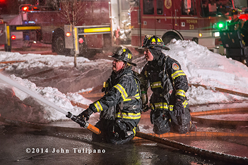 firemen covered with ice using a hose line