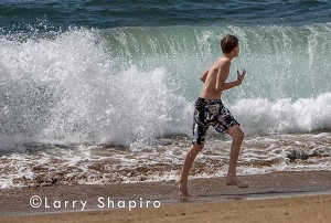 waves crashing on beach and scaring boy