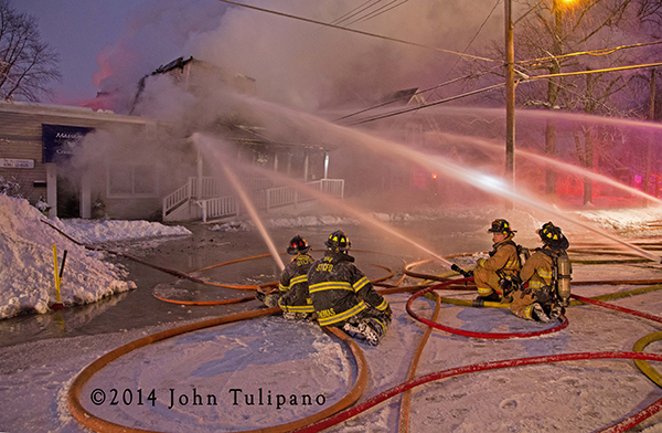 firemen with hose lines at winter fire scene