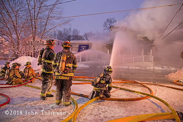 firemen with hose lines at winter fire scene