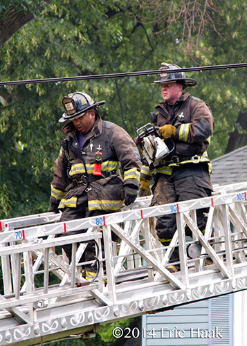 firemen with saw on E-ONE aerial ladder