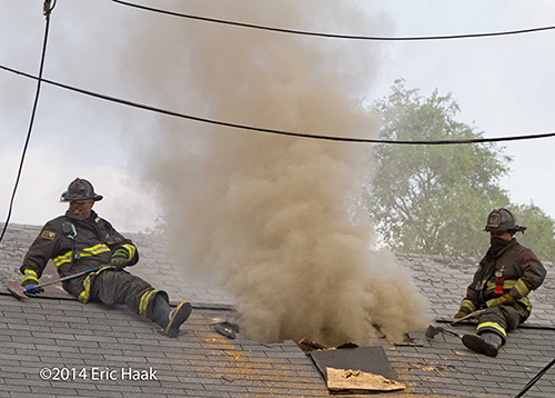 firemen with axes venting house with peaked roof in Chicago during a fire