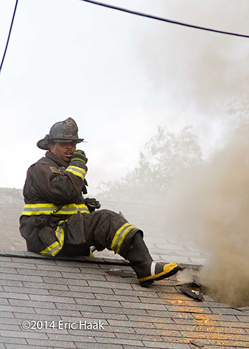 firemen with axes venting house with peaked roof in Chicago during a fire