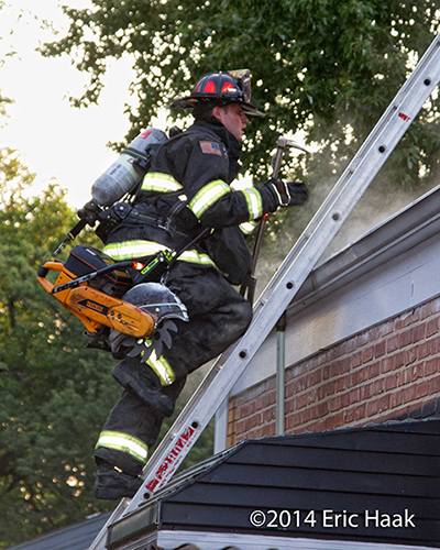 firefighter climbing ladder with saw and other tools