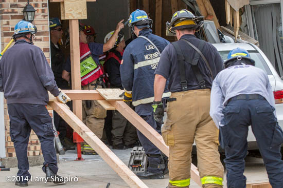 firefighters work to shore up a house damaged after an accident