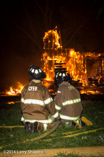 firemen with hose line at night fire scene