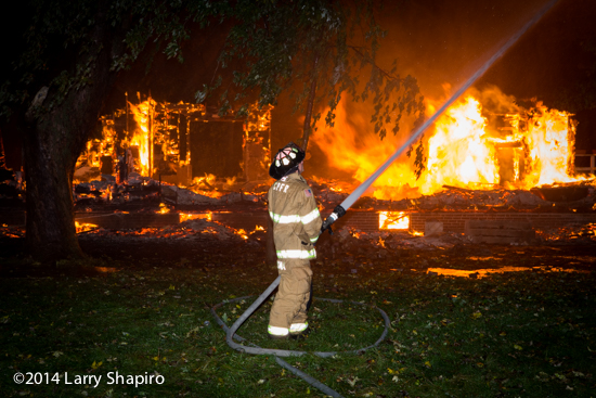 fireman at night with hose line against a backdrop of fire
