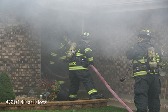 firemen entering house with hose line and heavy smoke