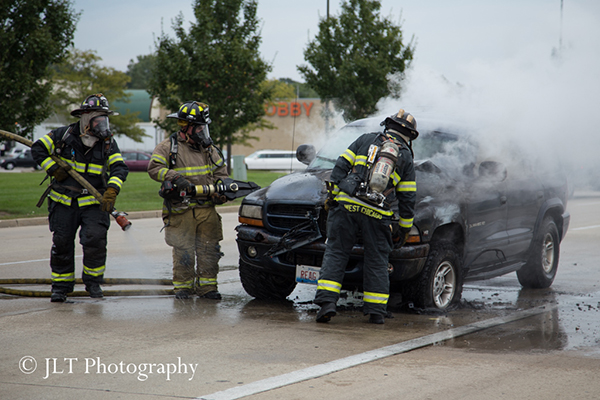 firemen inspect car after fire