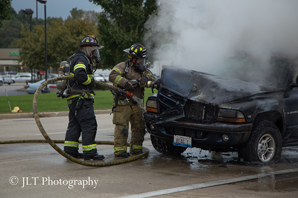 firemen inspect car after fire