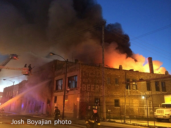 fire through the roof of a commercial building at dawn