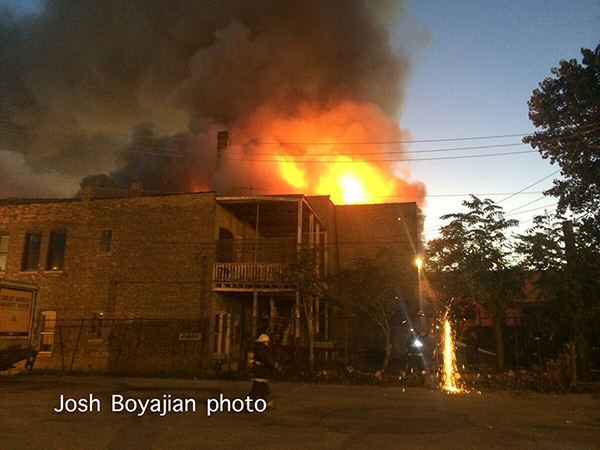 fire through the roof of a commercial building at dawn