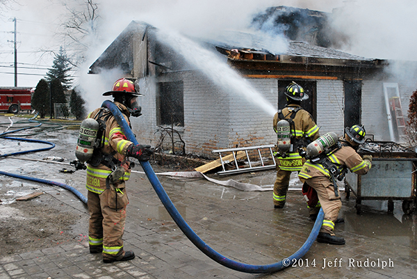 firefighters with hose line at house fire