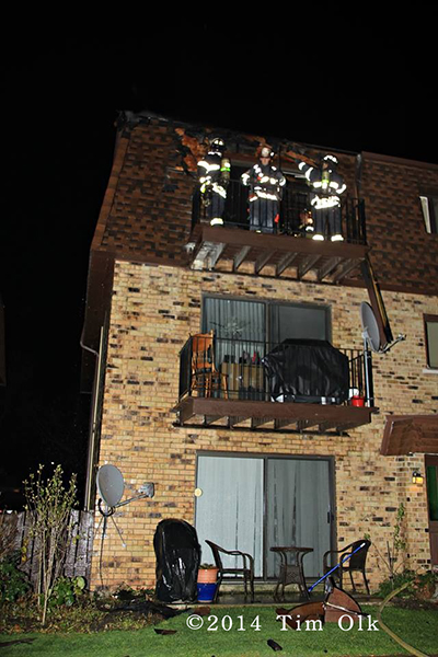 firemen on balcony with hose at night with mansard roof