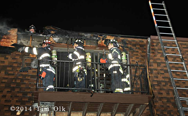 firemen on balcony with hose at night with mansard roof