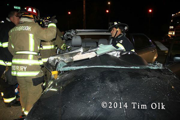 firemen work to free patients trapped in a car at night