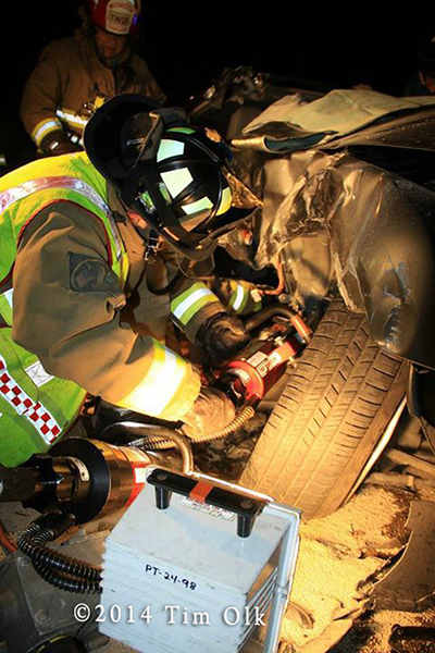 firemen work to free patients trapped in a car at night