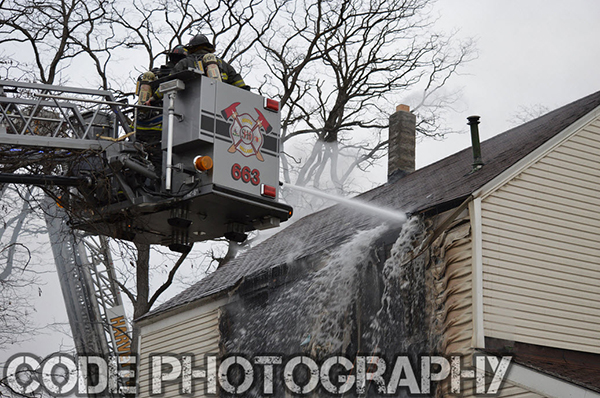 firemen in tower ladder at house fire 