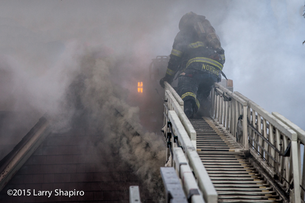 firemen on aerial ladder surrounded by smoke