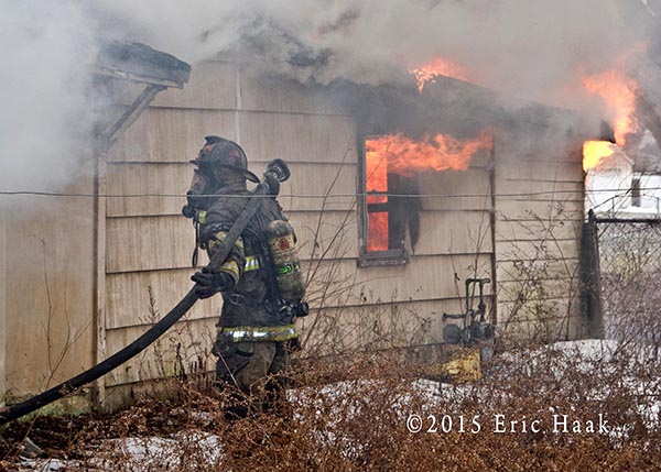 fireman stretching a line on a vacant house fire