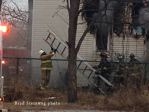 firemen maneuver ladder at fire scene