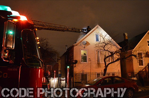 fire department ladder truck to roof of house at night