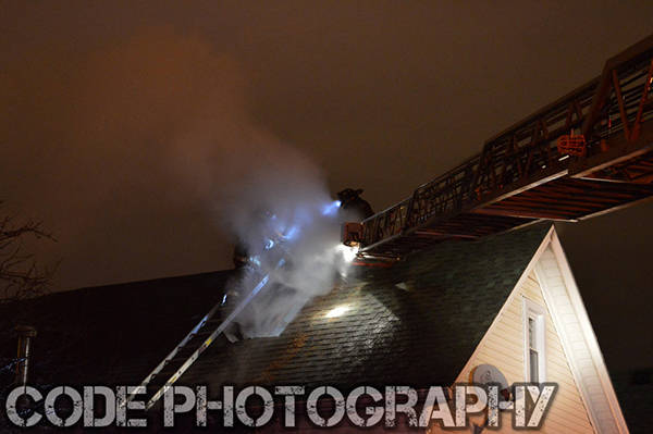 firemen on roof at house fire at night