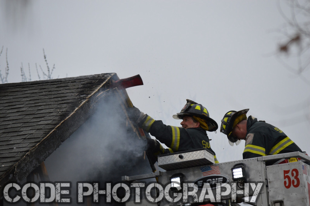 firemen overhaul roof of a house after a fire