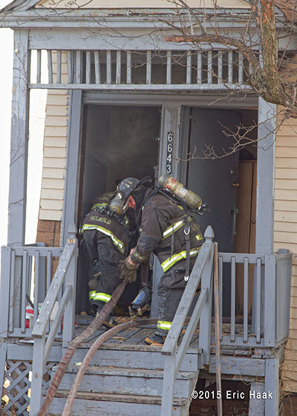 firemen with hose enter house on fire