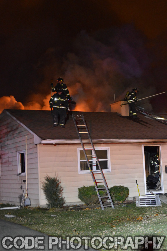firemen on roof of house fire at night