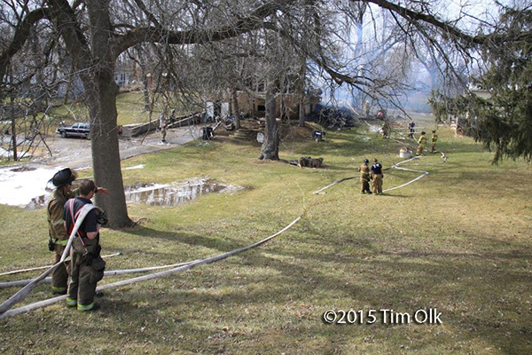 house fire scene with long hose lays