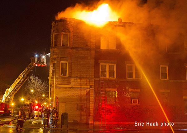 flames through roof of apartment building at night