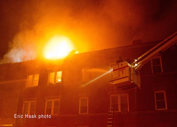 flames through roof of apartment building at night