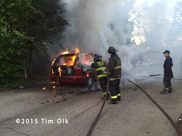 firemen extinguish a minivan engulfed in flames