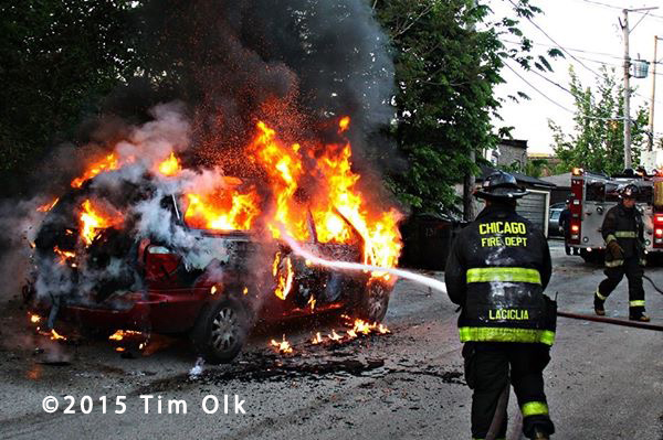 firemen extinguish a minivan engulfed in flames