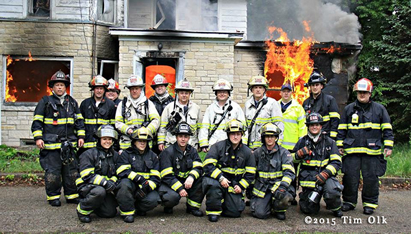 firefighters pose with burnin house