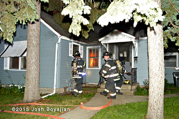 firemen prepare to take a line into a burning house