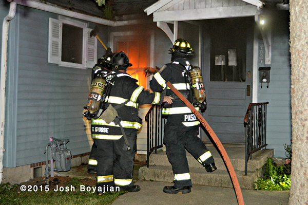 firemen prepare to take a line into a burning house