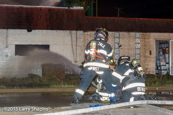 firemen with big hose line at night fire scene