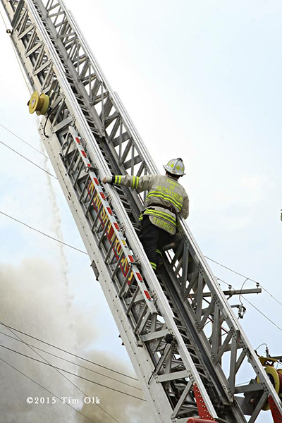 fire chief on aerial ladder surveying scene