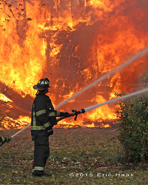 firefighter with hose line and massive flames