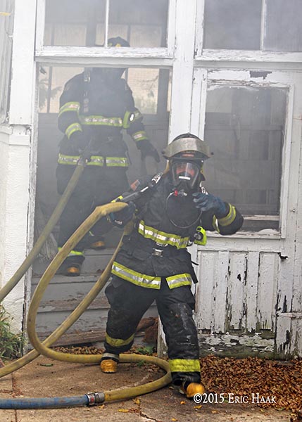 firefighter emerges from a house on fire during a training exercise