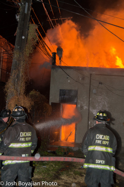 firefighters with hose line at night building fire