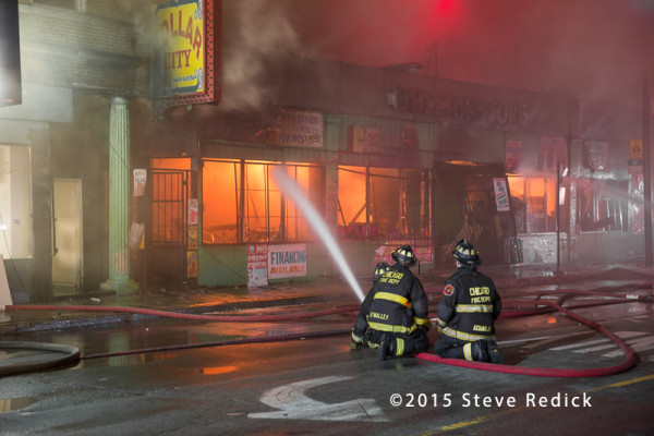 firefighters with hose line at night building fire