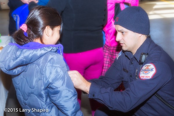 firefighter helps child with new winter coat
