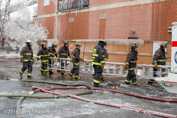 firemen carry frozen ladder covered with ice
