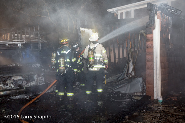 firefighters with house line at night fire scene on the rain